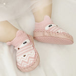 Pink baby socks with cartoon character design on a white background