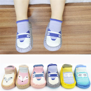 Children's socks with animal designs on a wooden floor.