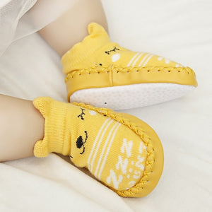Yellow baby shoes with white patterns on a light background