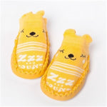Pair of yellow bear-shaped slippers with a smiley face on a white background