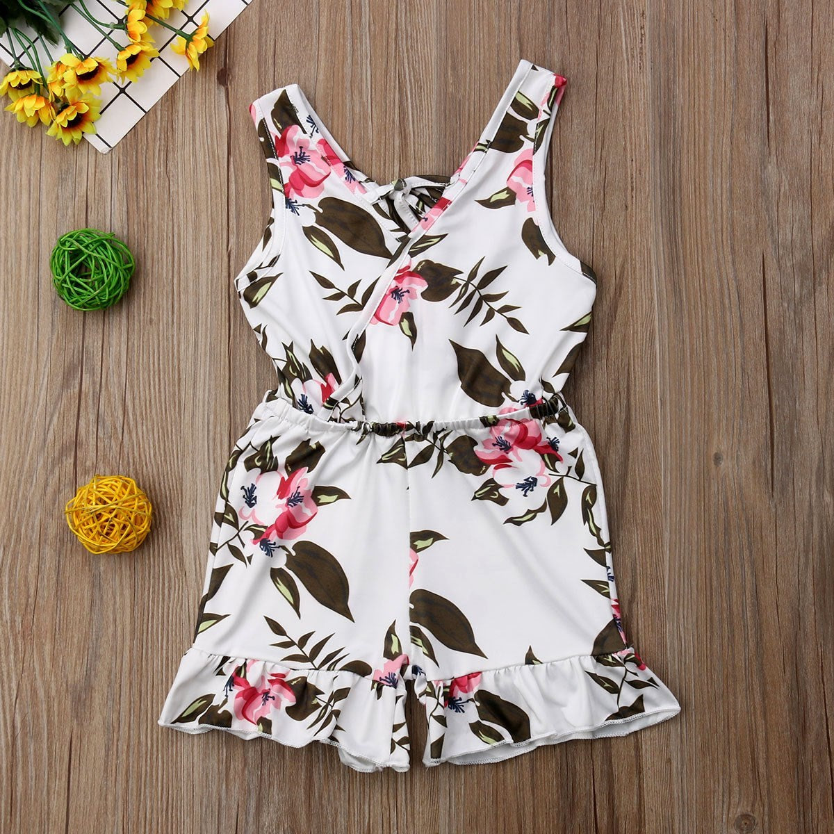 Floral romper on a wooden surface with decorative elements