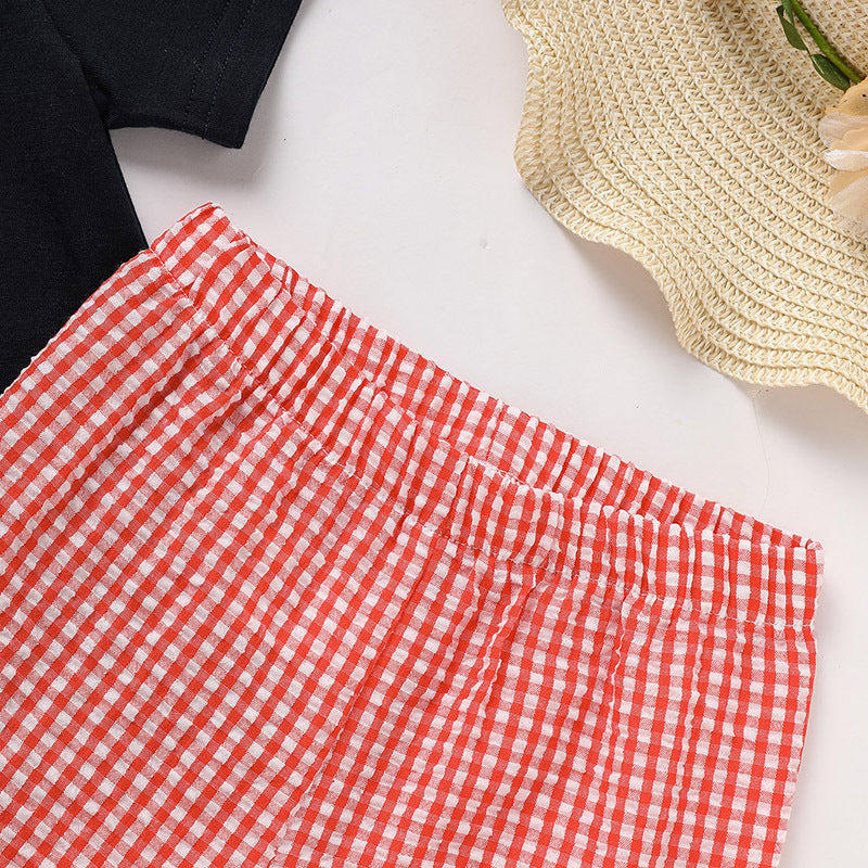 Red and white checkered pants on a white surface with a straw hat and black shirt in the background.