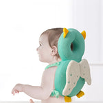 Baby wearing a green dinosaur-shaped anti-fall pillow on a white background