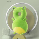 Green frog-shaped pillow on a stand with a plain background