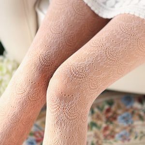 Close-up of patterned tights worn by a person sitting on a floral-patterned surface.