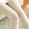 Close-up of beige lace-trimmed pants on a neutral background
