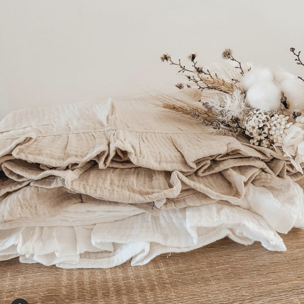 Stack of beige fabric with dried flowers on a wooden surface