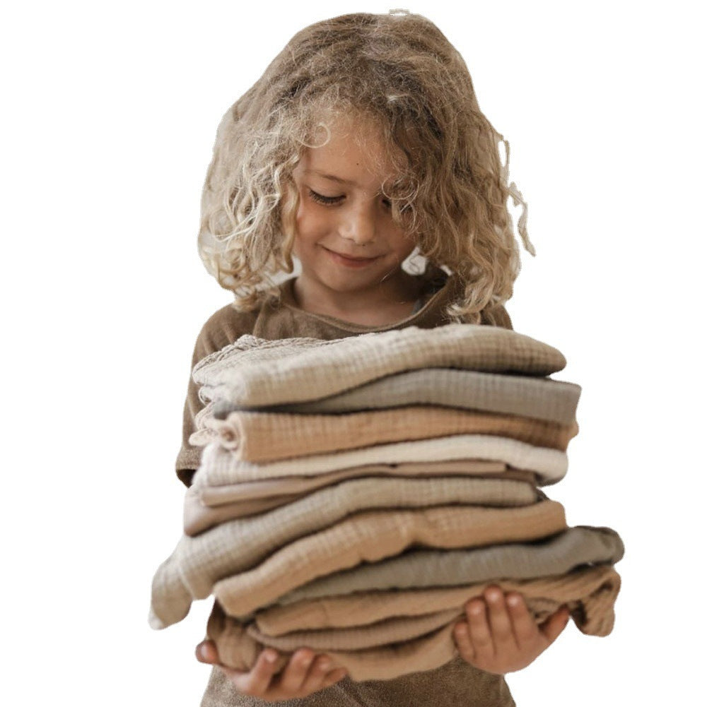 Child holding a stack of folded clothes on a white background
