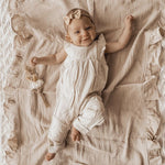 Baby in a white romper lying on a textured blanket