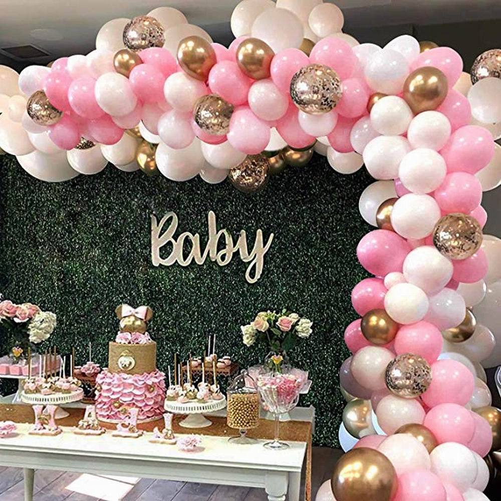Balloon arch with pink, white, and gold balloons at a baby shower.