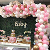 Balloon arch with pink, white, and gold balloons at a baby shower.