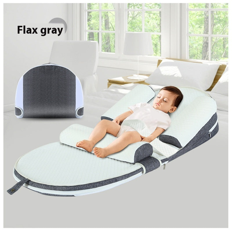 Baby lying on a gray and white baby seat with 'Flax gray' text above.