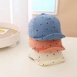 Three polka dot caps in blue, pink, and white on a light surface.