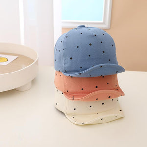 Three polka dot caps in blue, pink, and white on a light surface.