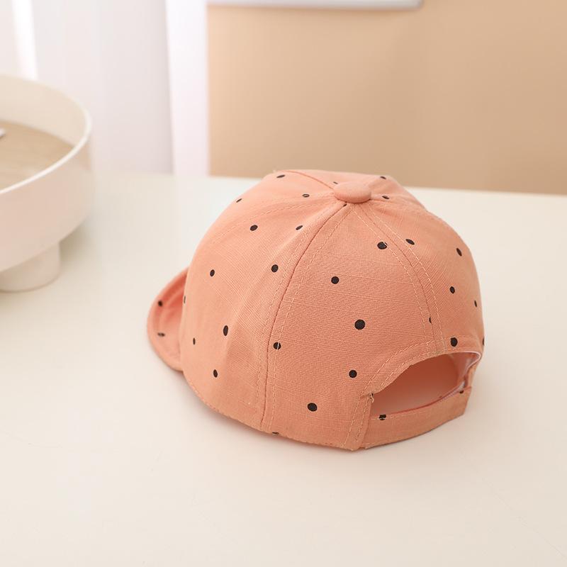 Pink cap with black polka dots on a white surface