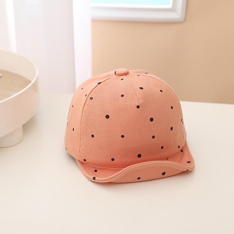 Pink cap with black polka dots on a white surface