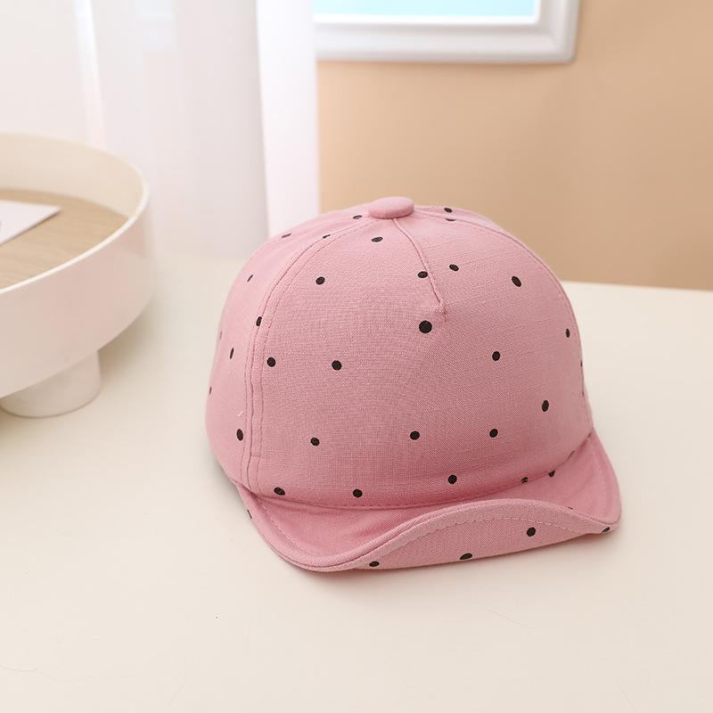 Pink cap with black polka dots on a light surface