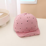 Pink cap with black polka dots on a light surface