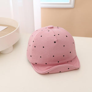 Pink cap with black polka dots on a light surface