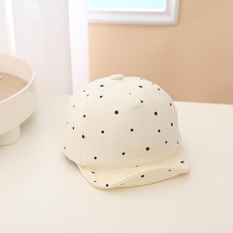 White baby hat with black polka dots on a light surface