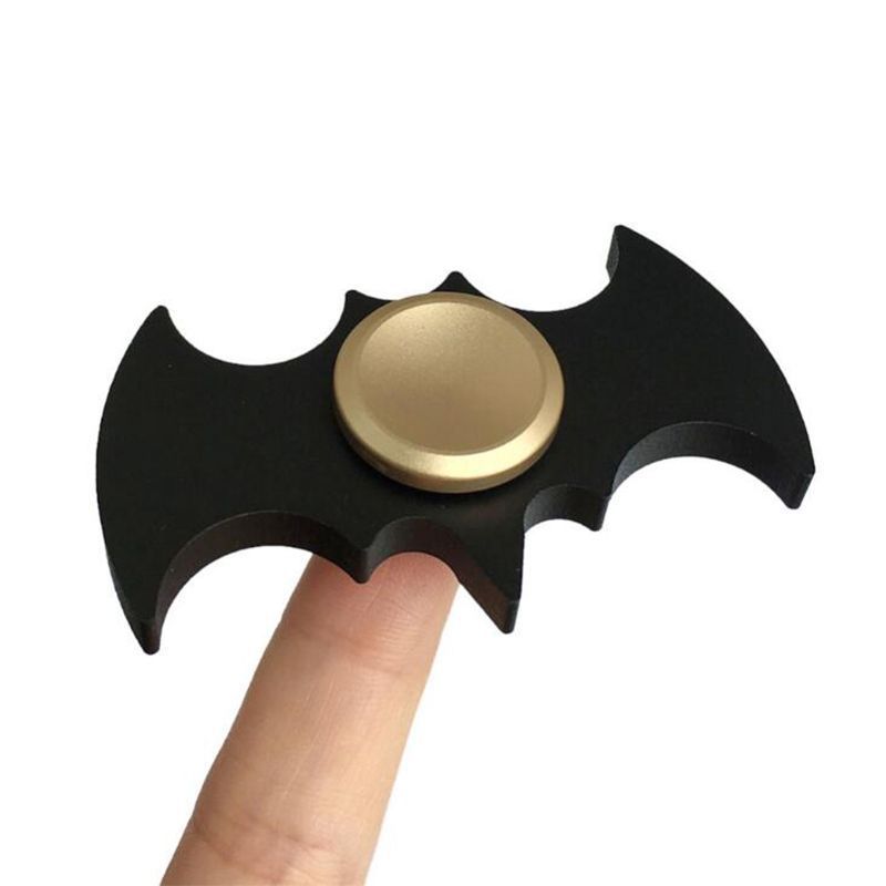 Fidget spinner shaped like a bat symbol held by a finger on a white background