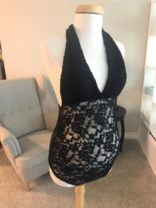 Black lace top on a mannequin in a room with a sofa and lamp.