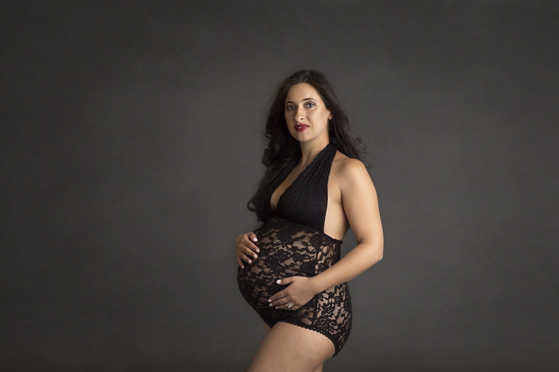 Woman wearing a black lace bodysuit against a dark background