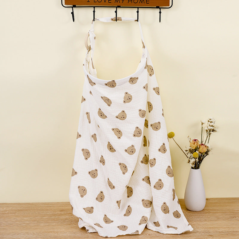 White apron with bear pattern on a wooden surface with a vase of flowers in the background.