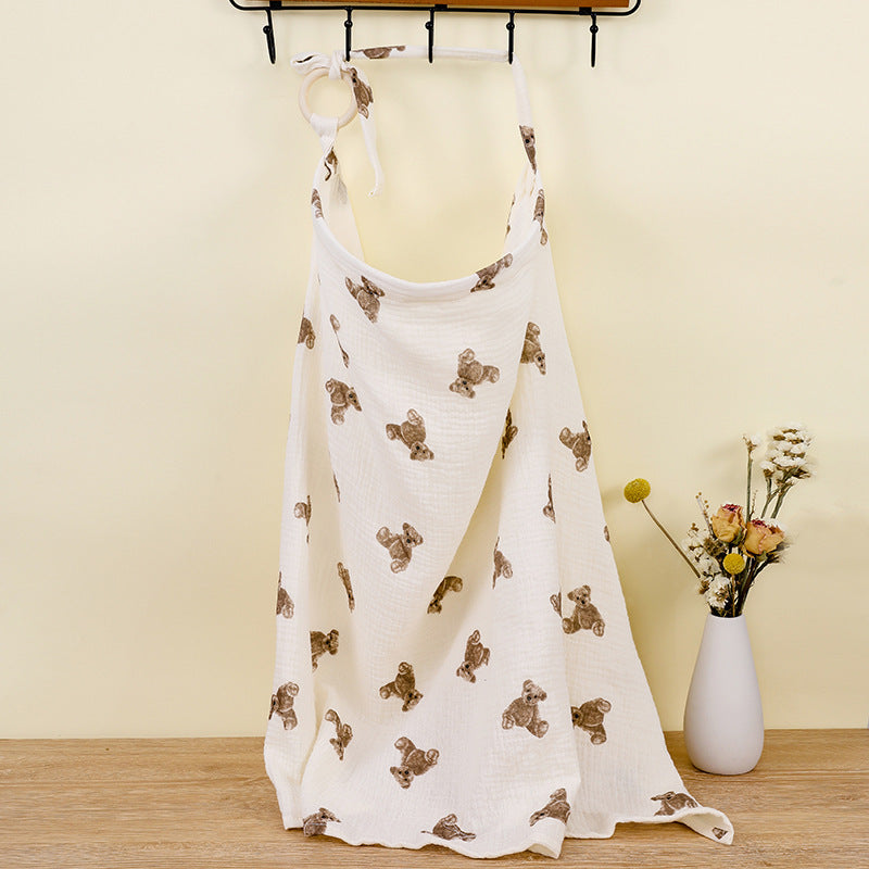 White dress with brown bear prints on a wooden floor with a vase of flowers in the background.