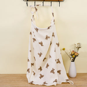 White dress with brown bear prints on a wooden floor with a vase of flowers in the background.