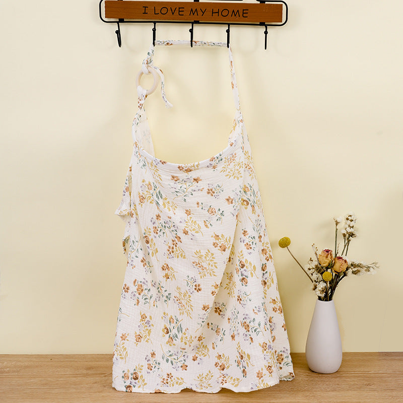Floral dress hanging on a rack with a vase of flowers on a wooden floor.
