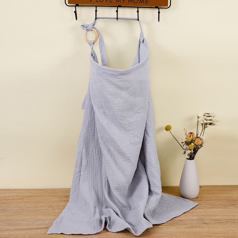 Light blue dress on a hanger against a beige wall with a vase of flowers on a wooden floor.