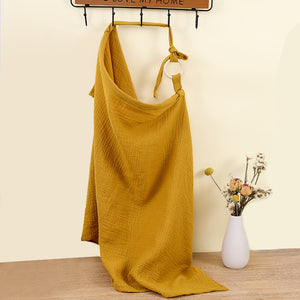 Mustard yellow dress hanging on a rack with a vase of flowers on a wooden floor.