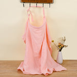 Pink dress with thin straps on a wooden floor with a vase of flowers in the background.