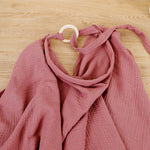 Pink fabric draped over a hanger on a wooden surface