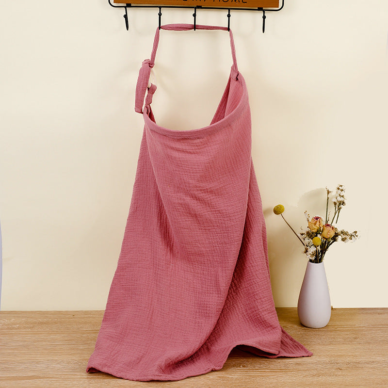 Pink apron hanging on a hook with a vase of flowers on a wooden surface.