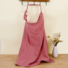 Pink apron hanging on a hook with a vase of flowers on a wooden surface.