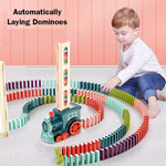Child playing with a colorful domino set and train toy on a pink floor.