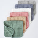 Set of five textured fabric baby bibs in various colors on a white background