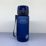 Blue water bottle with black lid and handle on a light gray surface with white background