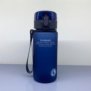 Blue water bottle with black lid and handle on a light gray surface with white background