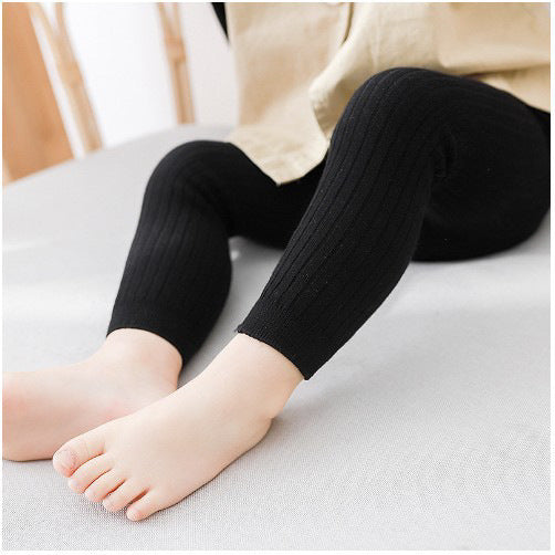 Black tights worn by a child on a light-colored surface