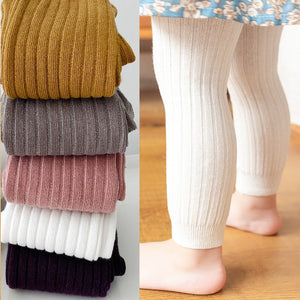 Stack of colorful ribbed tights on a white background with a child wearing beige ribbed tights.