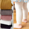 Stack of colorful ribbed tights on a white background with a child wearing beige ribbed tights.