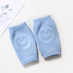 Pair of blue knee pads with smiley face designs on a light background