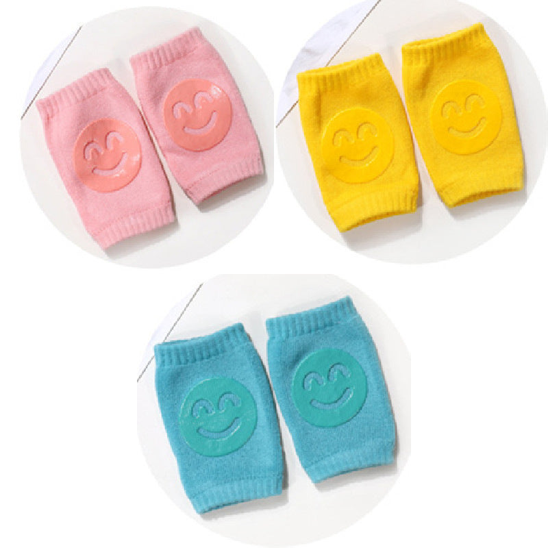 Set of colorful baby knee pads with smiley face designs on a white background