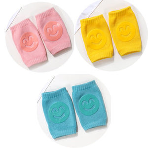 Set of colorful baby knee pads with smiley face designs on a white background