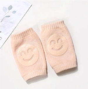 Pair of pink baby leg warmers with smiley face design on a white background