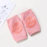 Pair of pink knee pads with smiley face designs on a white background