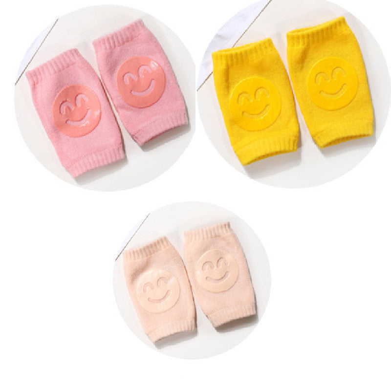 Set of baby knee pads in pink, yellow, and peach on a white background